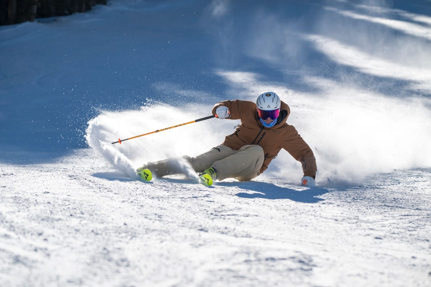 Tomas Mical carving a turn through fresh snow in the shade of the trees